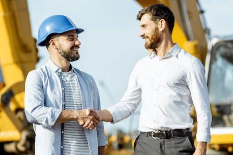 Apretón de manos entre un profesional de la construcción y un comercial en obra
